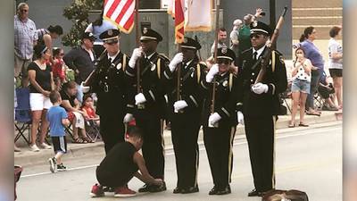 Boy ties honor guard's shoe during July 4 parade