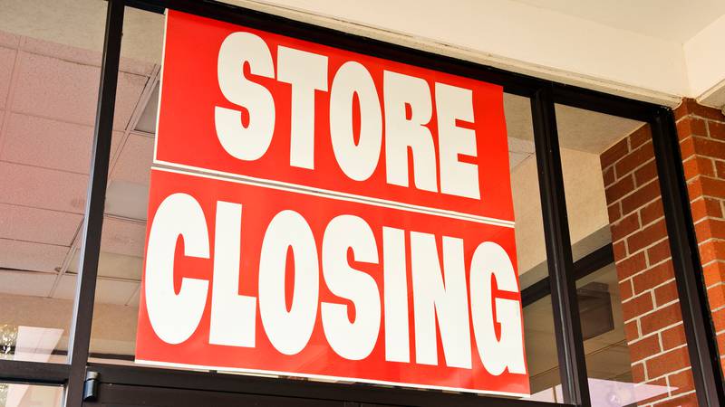 Red store closing sign hung in window of a retailer.