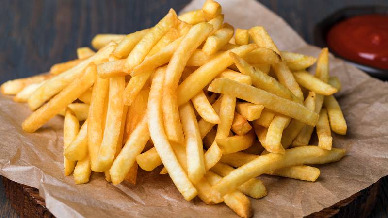 Tasty french fries on cutting board