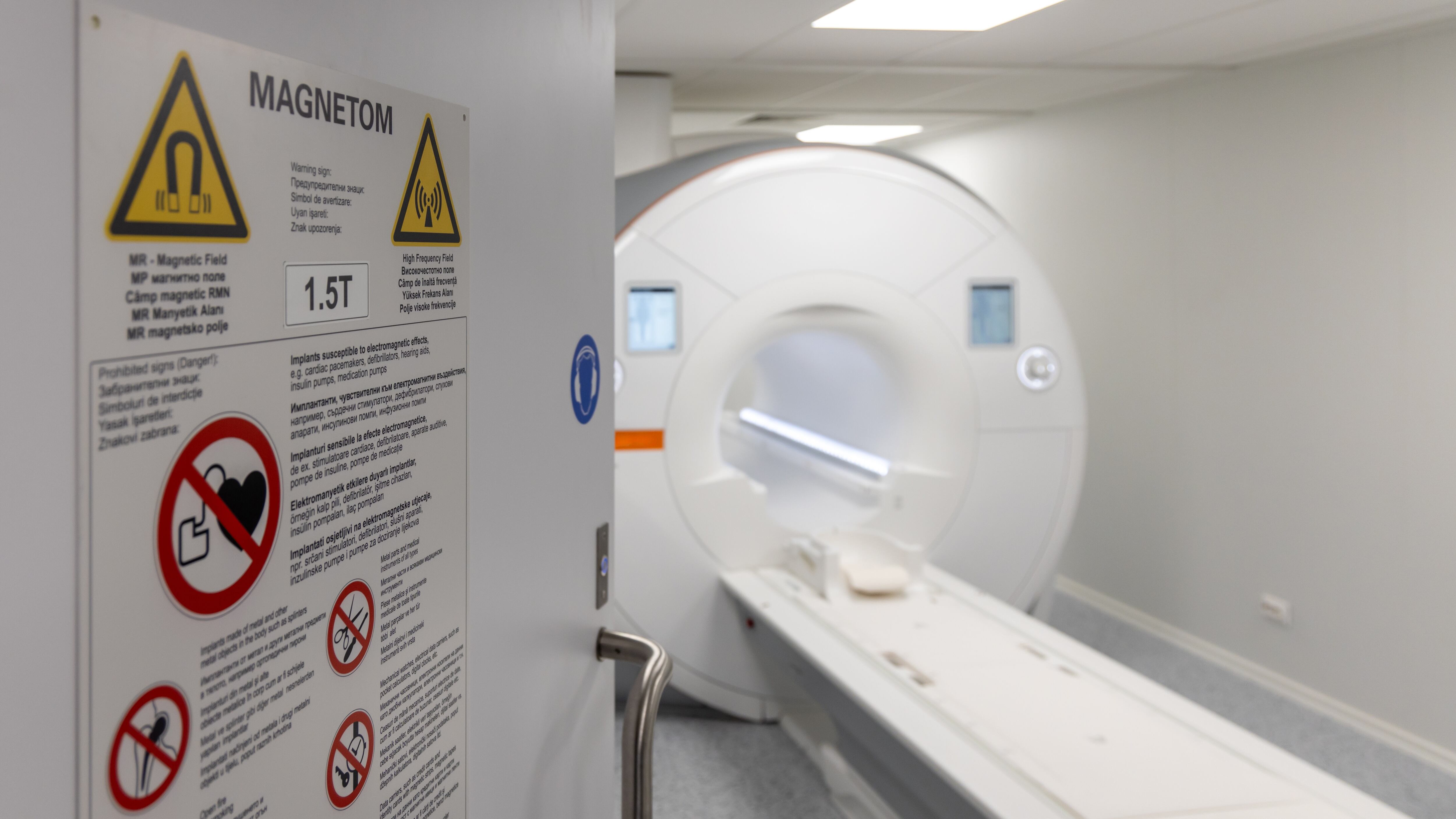 MRI scanner room entrance with multilingual safety warning signs. Modern hospital magnetic resonance imaging technology for medical diagnostics and patient care.
